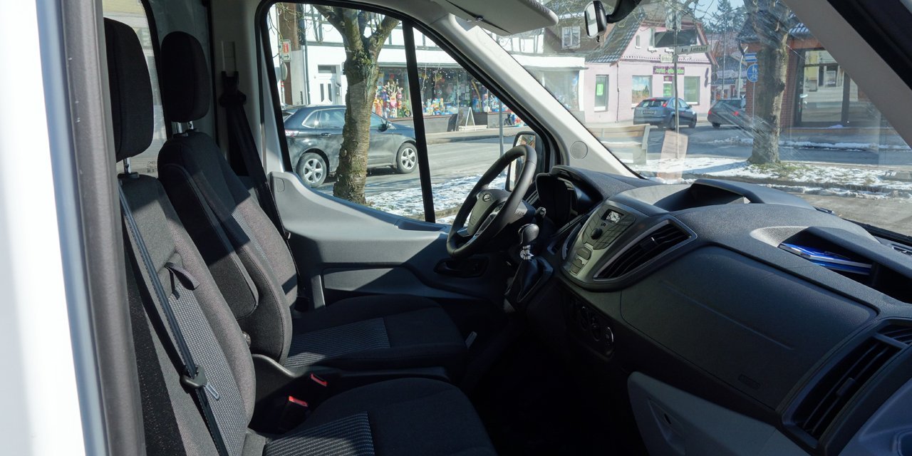 Innenansicht des Kleinbusses, Blick auf das Armaturenbrett und die Vordersitze durch die Beifahrertür.